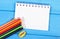 Colorful crayons, sharpener and notepad on blue boards, school accessories, copy space for text