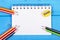 Colorful crayons, sharpener and notepad on blue boards, school accessories, copy space for text