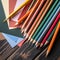 Colorful crayons and stack of drawing papers on wooden table. Square frame.,