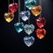 Colorful crystal hearts hanging on strings on black background.