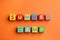 Colorful cubes with phrase SUMMER CAMP on orange background, flat lay