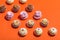 Colorful cupcakes in three rows on orange background.