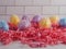 Colorful decorated Easter Eggs with pink paper shred on a white counter top with a white subway tile background.  Holiday