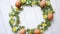 Colorful decorative Easter eggs wreath on white wooden table background