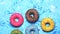 Colorful delicious sweet donuts spinning on a blue background. Slow motion video, closeup.