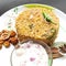 Colorful Delicious yummy prawn briyani with prawn fry in center with prawn fry and raita plated beautifully in white plate with