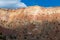 A colorful desert cliff face illuminated a break in the clouds