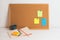 Colorful different stickers pined on the corkboard with notepad and coffe on white wooden table, horizontal. Planning concept