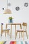 Colorful dining room interior with a table, chairs, striped rug, pastel chandelier and hanging plates on the wall