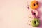 Colorful donuts with icing on pastel pink background. Sweet orange, green, pink doughnuts with pistachio, chocolate