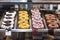 Colorful donuts with sprinkles in a restaurant`s display case, sorted on a nirosta storage