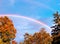 Colorful double rainbow with maple trees and blue sky