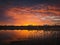 Colorful and dramatic sunset sky reflecting on pond water. Silent evening scene at Delia lake. Vibrant sundown clouds at the