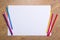 Colorful drawing pencils and blank paper on wooden table