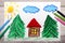 Colorful drawing: small house surrounded by coniferous trees.