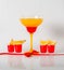 Colorful drink in a margarita glass, red and orange combination, four drinks in a shotglass,red bow