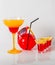 Colorful drink in a margarita glass, red and orange combination, four drinks in a shotglass, sunglasses
