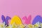 Colorful Easter bunnies, eggs, daffodils border on pink background, flat lay with space for text. Happy Easter! Purple, pink,