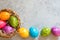 Colorful easter eggs in basket on concrete background