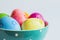 Colorful easter eggs in green spotted bowl on light background