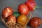 Colorful Easter eggs in a knit basket and red tulip on a wooden table.