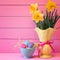 Colorful Easter Eggs in Nest with Daffodils in Vase on Pink Boards Background with room or space for copy, text, or your words.