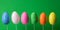 Colorful Easter eggs on sticks glittering on green background.