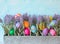 Colorful Easter Eggs Still Life Display with Lavender Flowers in Metal Planter against Blue Sky Background
