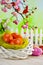 Colorful Easter eggs, white nest and fence on wooden table