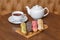 Colorful eclair cakes with cream and teapot on wooden board