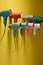 Colorful electric hair dryers hanging on a yellow wall in a studio