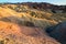 Colorful Eroded Ridges of Zabriskie Point, dry mudstone mountains, volcanic shaped, lifeless landscape during setting sun light