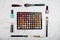 Colorful eyeshadow palette with brushes, lipstick and nail varnish on marble background