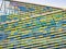 Colorful facade of a building with a vibrant rectangular window pattern. Glasses change color with sun time