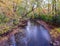 Colorful fall leaves on trees and in the water of the Minnehaha Creek in Minneapolis, Minnesota - long exposure of the flowing cre