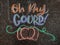 Colorful fall-themed chalk art on a driveway that says, Oh my gourd! with a pumpkin underneath.