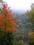 Colorful fall trees overlooking small lake with fog rolling over mountain