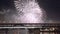 Colorful fireworks reflect from water, beautiful bridge scenery