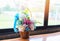 Colorful flower pot on the wooden table with window Multi-colored bouquet of different flowers on the windowsill