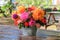 Colorful flowers: roses, asters, dahilia in the apple garden on a wooden table. Bright rural design. Sunny day