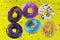 Colorful flying doughnuts with sprinkles on yellow background.