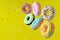 Colorful flying doughnuts with sprinkles on yellow background.