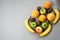 Colorful fresh fruit on Gray table. Orange, banana, apples, kiwi
