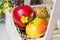 Colorful fresh red yellow apples pears in vintage wood box on straw, yellow flower, outdoor in garden, summer