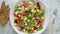 Colorful fresh vegetable salad with feta cheese in a white deep bowl closeup on a stone table