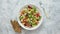 Colorful fresh vegetable salad with feta cheese in a white deep bowl closeup on a stone table