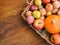 Colorful freshly picked plums Mirabelles red yellow green apples pumpkin in wicker basket on wood garden table. Autumn fall