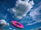Colorful frisbee flies against cloudy blue sky