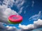 Colorful frisbee flies against cloudy blue sky