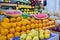 Colorful fruit stand with oranges, sliced watermelons, apples, and more